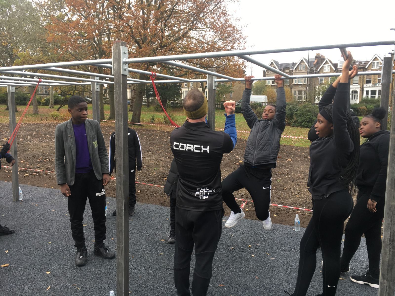 A Steel Warriors coach supporting participants on the bars