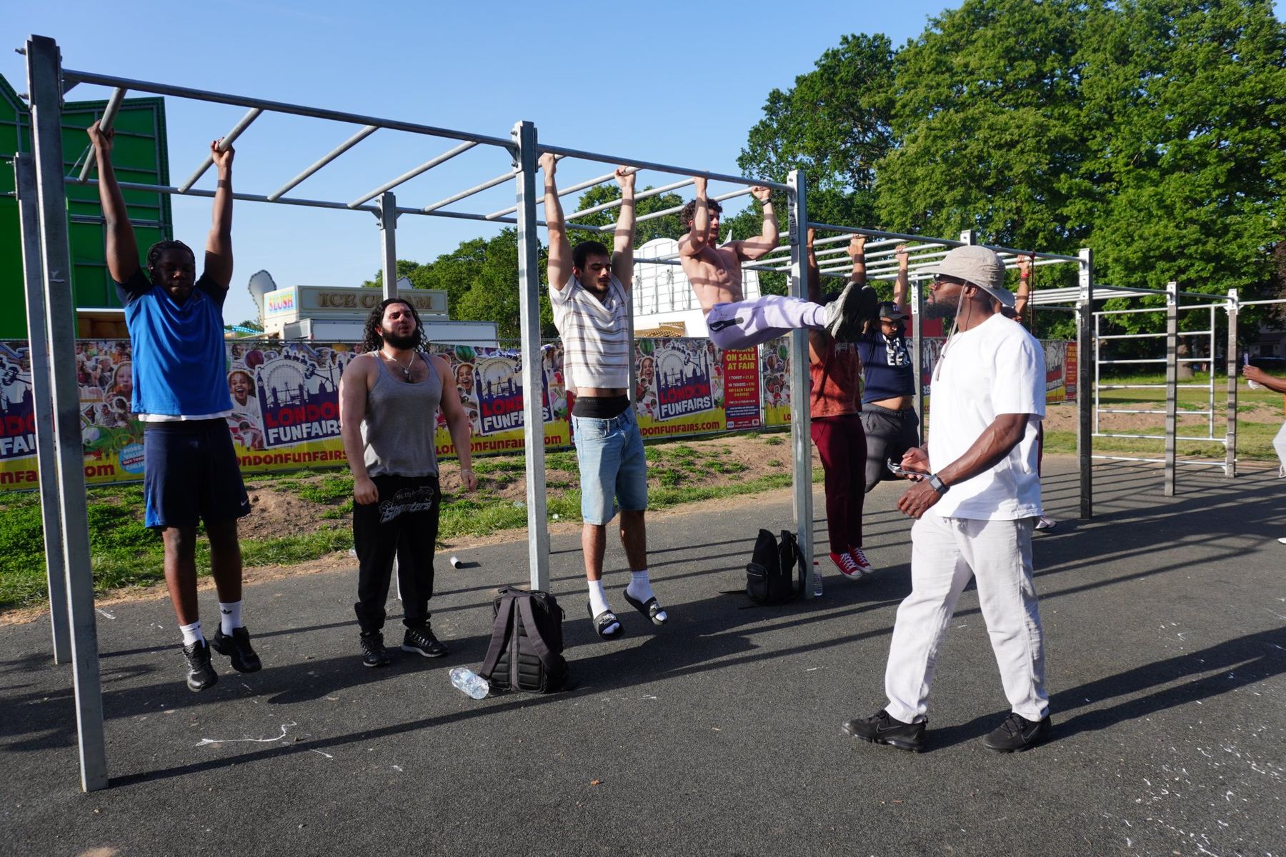 People training on the bars at our Pymmes Park gym while a coach looks on