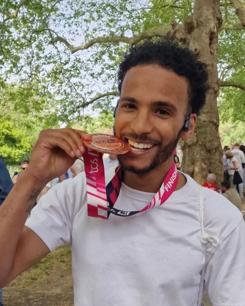A Steel Warriors runner biting his London Marathon finisher's medal