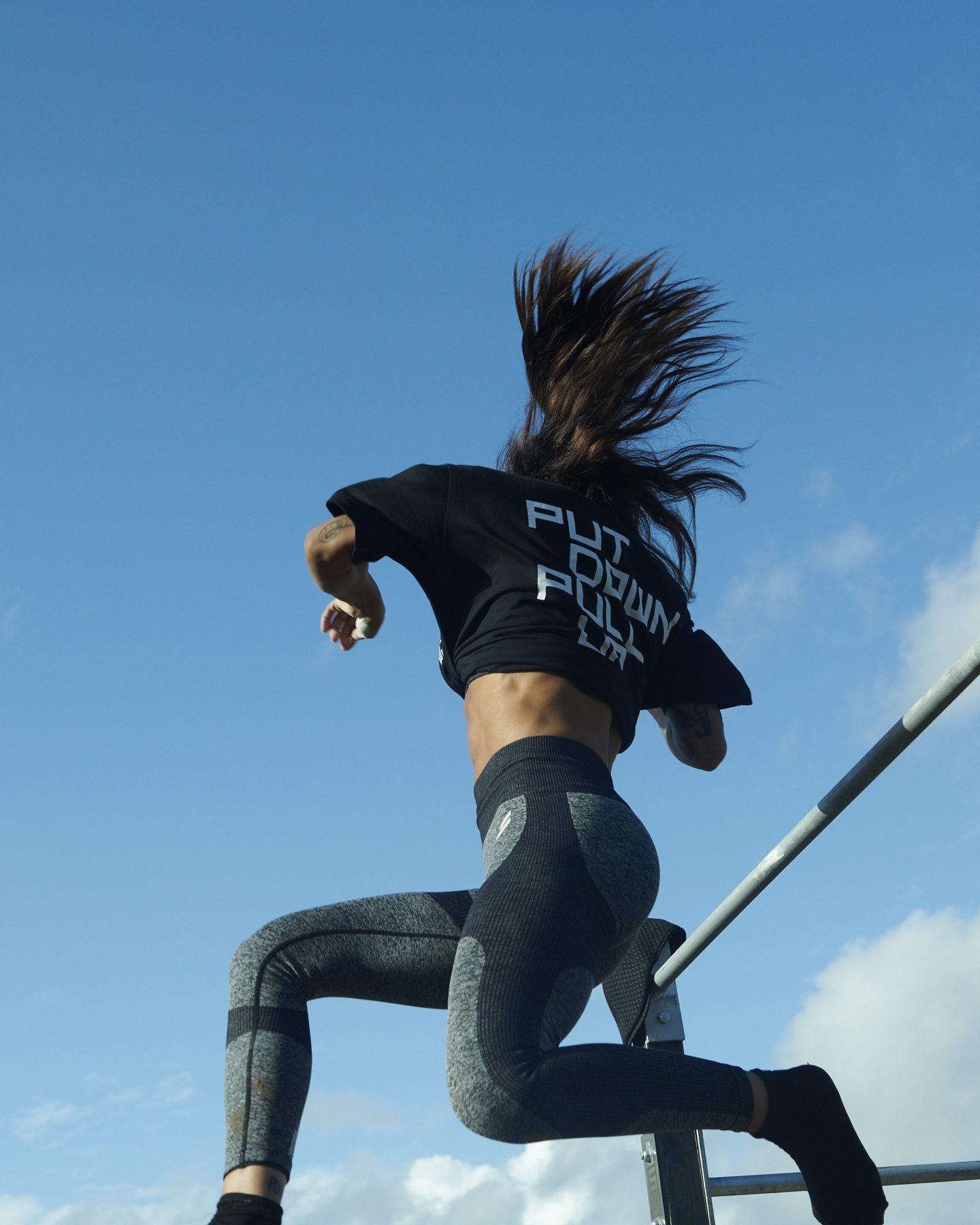 An athlete leaping onto the bars in a Put Down, Pull Up t-shirt
